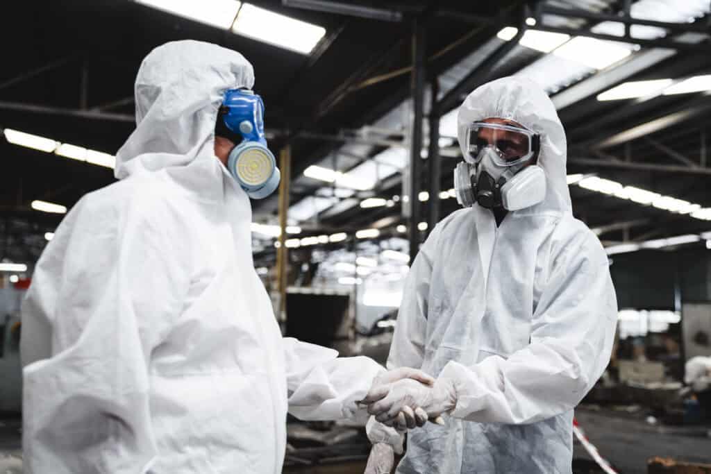Scientist workers wear protective suit shack hand with team when working success. Protecting Against Hazards and Contamination